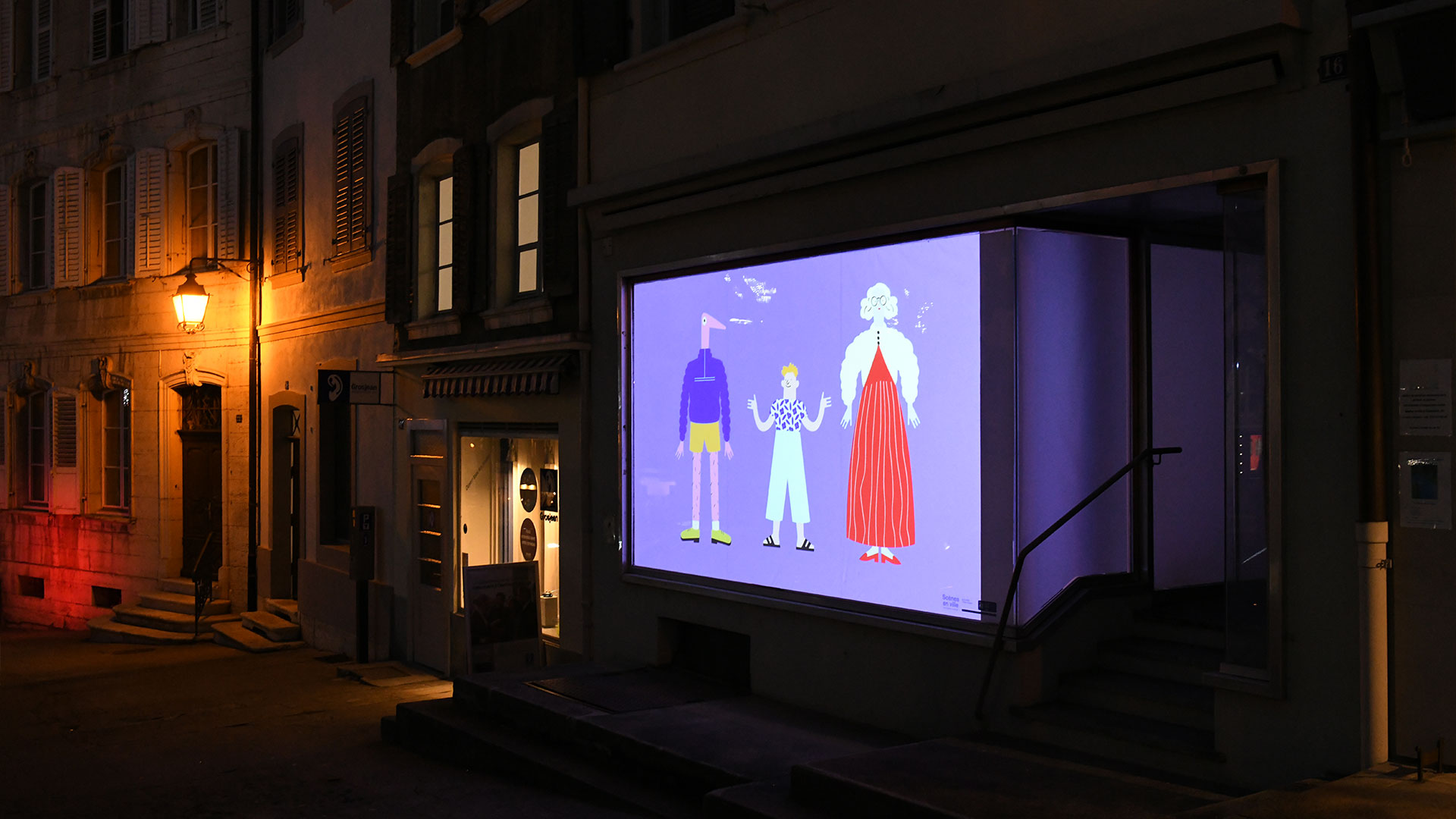 Projection vidéo sur une vitrine en vieille ville de Porrentruy montrant des illustrations colorées.