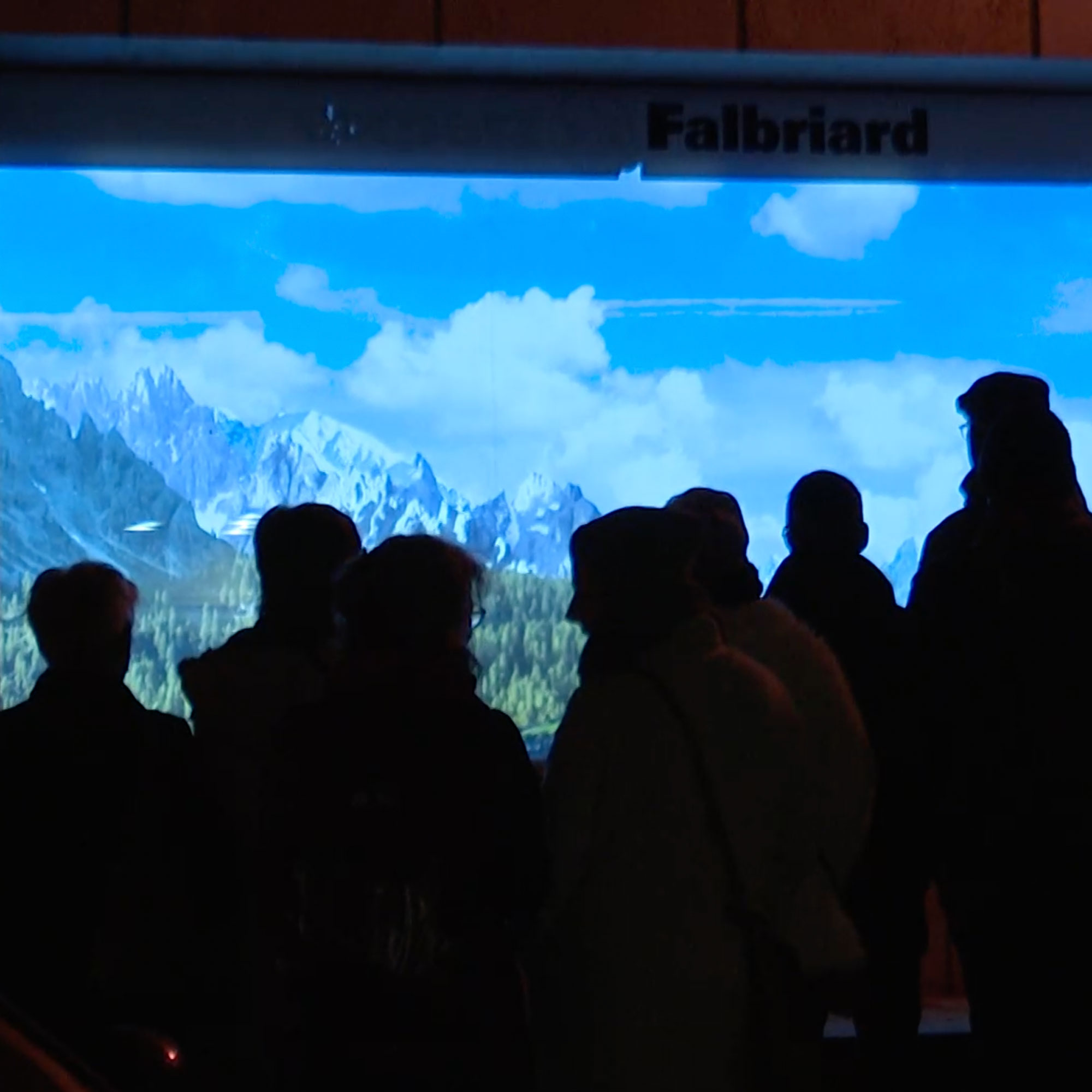 Une foule regardent une vidéo projetée sur une vitrine la nuit à Porrentruy. C'est le vernissage de Scènes en ville !